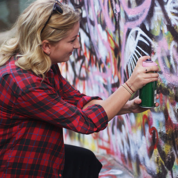 Mujer pintando una pared con aerosol.