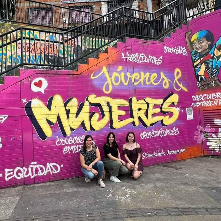 Grupo de mujeres frente a un grafitti que hace honor a la mujer.