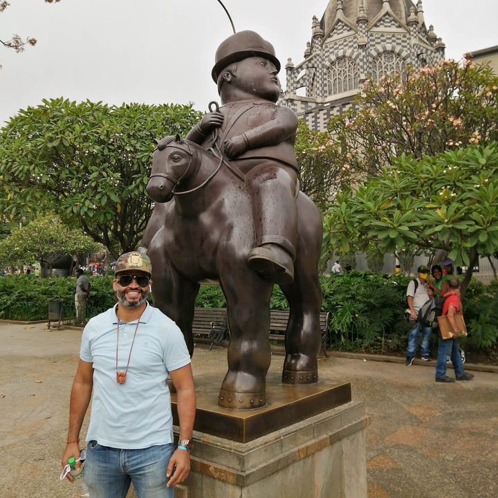 Hombre junto a escultura de arte del artista Botero.