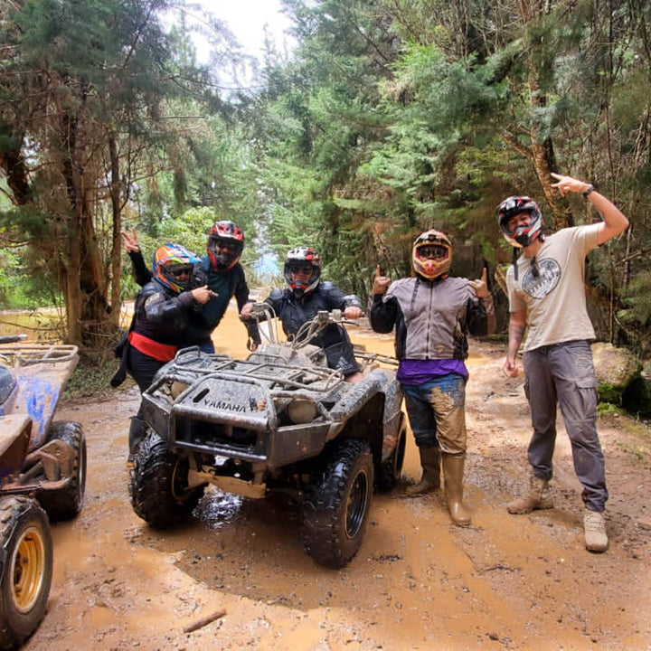 Grupo de amigos disfrutando de manejar ATVs por caminos abiertos naturales, llenos de lodo.