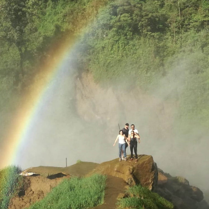 Familia en una cascada contemplando el arcoíris. 